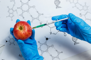 GMO Scientist Injecting Green Liquid from Syringe into Apple - Genetically Modified Food Concept